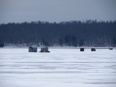 [Closer view of three of the shacks, the car and the snowmobile.]